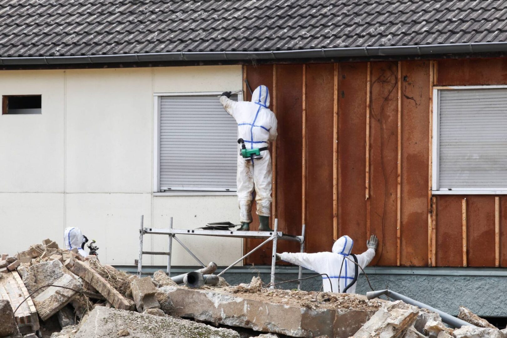 Workers in hazmat suits demolishing a building.