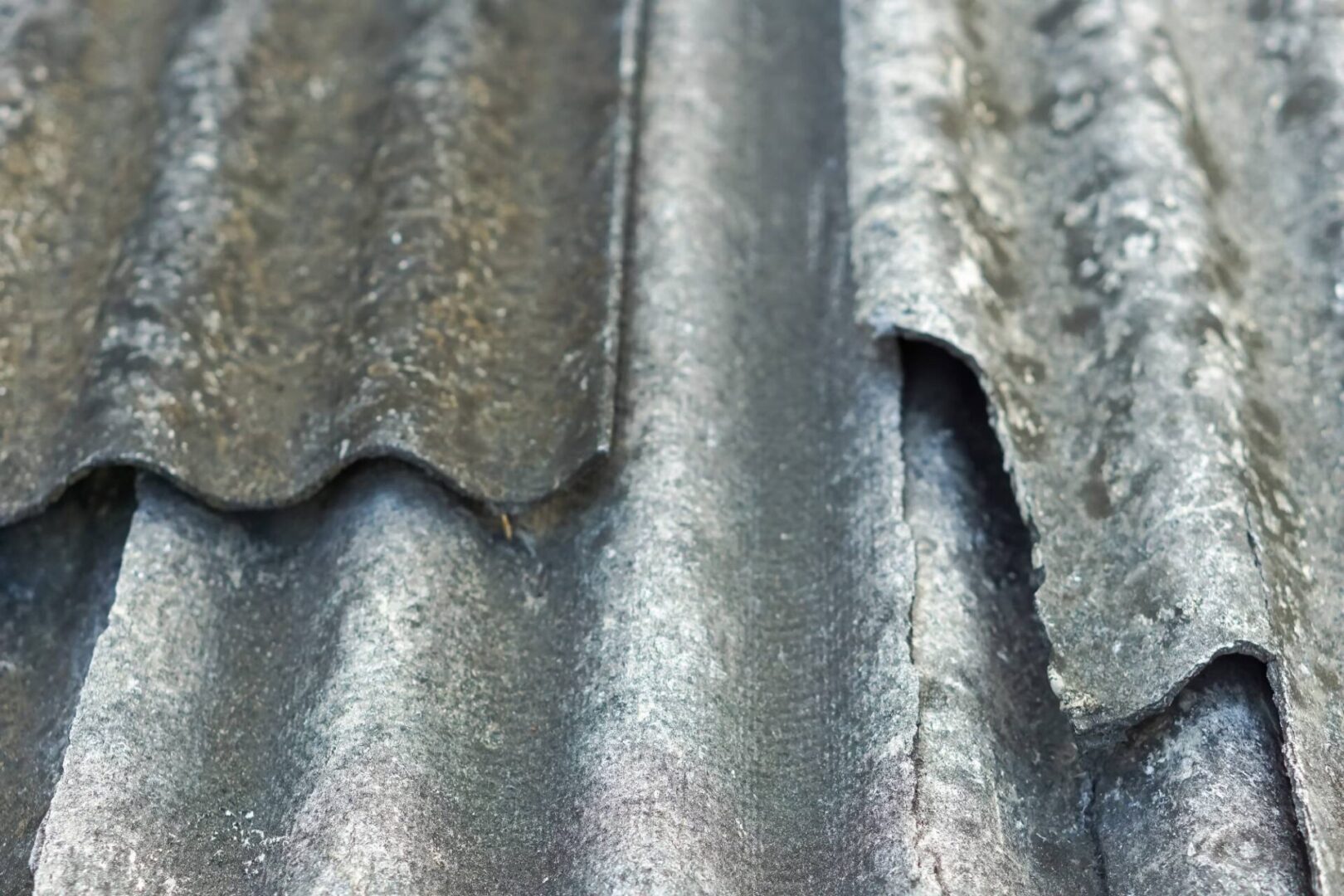 Here's an alt tag for the image: Weathered, damaged asbestos roofing.