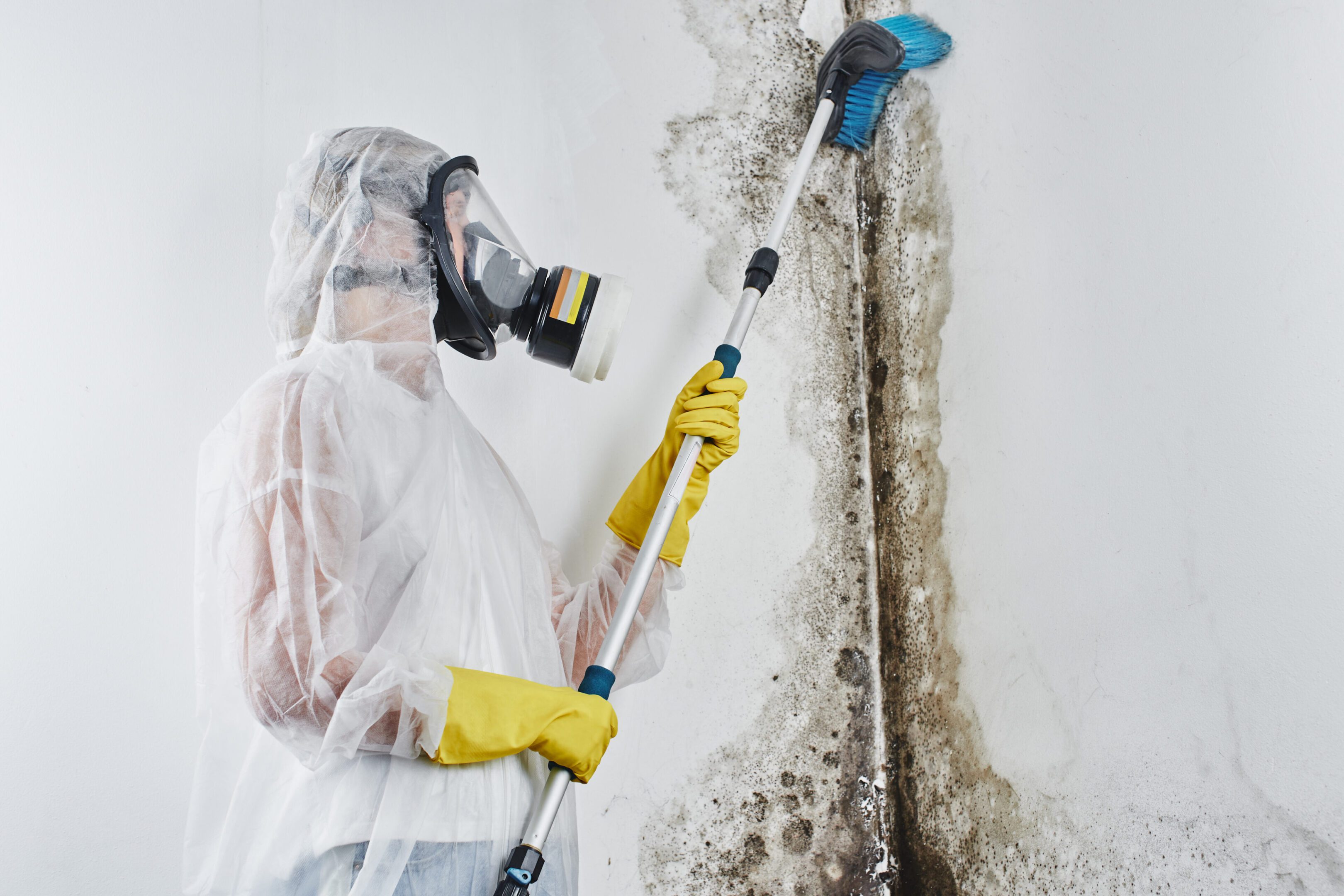 A person in white and yellow holding a mop.